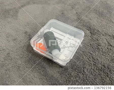 A tailor's sewing kit on a table. Needles, thread, and fabric fo A tailor's sewing kit on a table. Needles, thread, and fabric fo 136792156