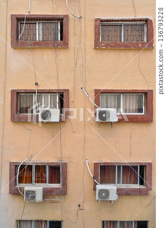 Air conditioning external units with large fans on old building facade wall near windows, many untidy cables near Air conditioning external units with large fans on old building facade wall near windows, many untidy cables near 136793228