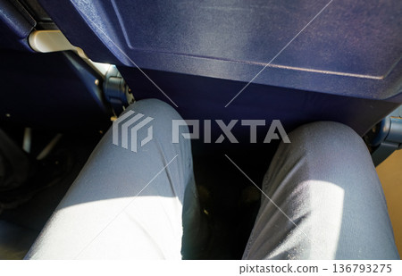 Looking down at narrow leg space in low cost airline seat, knees touching back rest at front Looking down at narrow leg space in low cost airline seat, knees touching back rest at front 136793275