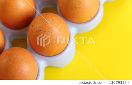 Beige coloured eggs on yellow board, closeup detail, space for text right down corner Beige coloured eggs on yellow board, closeup detail, space for text right down corner 136793324