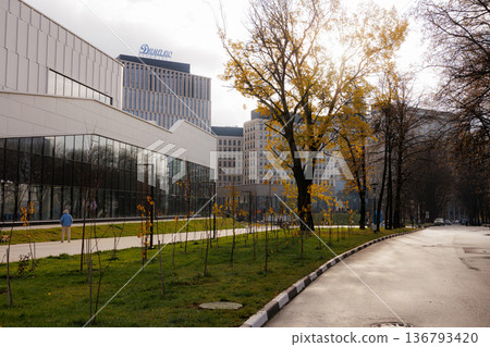 Vibrant autumn scene with golden leaves near modern architecture in a serene urban setting Vibrant autumn scene with golden leaves near modern architecture in a serene urban setting 136793420