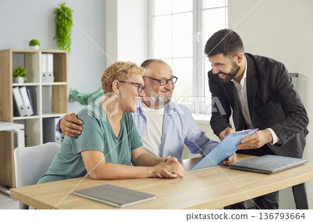 Senior couple meets friendly financial advisor to review documents in office Senior couple meets friendly financial advisor to review documents in office 136793664