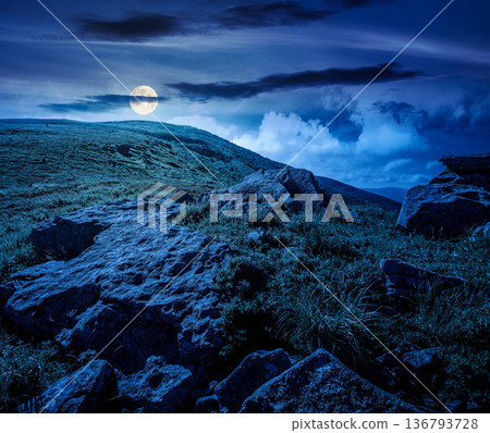 mountain landscape in summer under dark sky at night. lush green grass and sharp rocks on steep hillside in full moon light. beautiful view of remote place in mysterious alpine environment for fantasy mountain landscape in summer under dark sky at night. lush green grass and sharp rocks on steep hillside in full moon light. beautiful view of remote place in mysterious alpine environment for fantasy 136793728