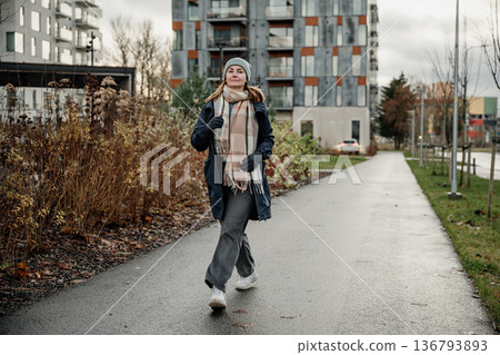 Woman walks on a path in a modern neighborhood during a cloudy day in autumn 136793893