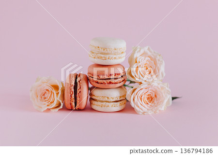 Tasty french macarons with tender rose flowers on a pink pastel background. 136794186