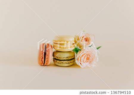 Tasty french macarons with tender rose flowers on a peach pastel background. 136794510