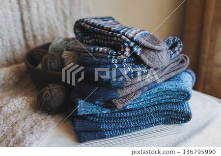 Hand knitted socks with needles and yarn ball in a basket. Concept for handmade and hygge slow life. 136795990