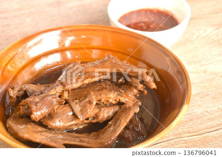 boiled slice duck foot and wing in black soybean herb soup in bowl dipping spicy sour chili sauce boiled slice duck foot and wing in black soybean herb soup in bowl dipping spicy sour chili sauce 136796041