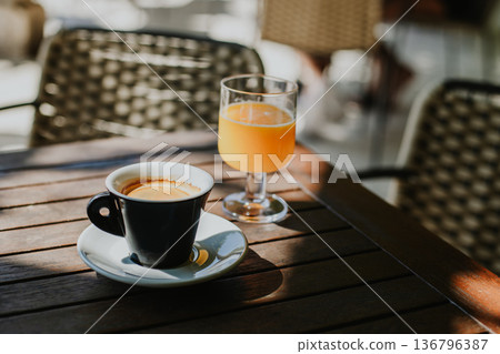 Cup of black coffee and fresh orange juice on a table in a street cafe. Cup of black coffee and fresh orange juice on a table in a street cafe. 136796387