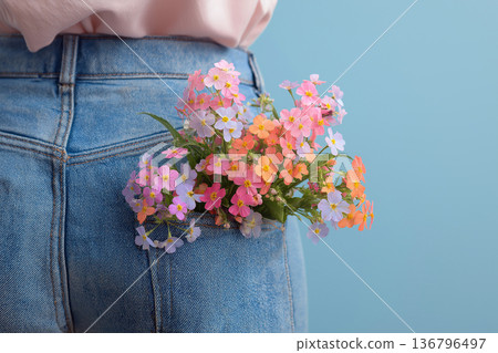 Bouquet of spring flowers tucked into jeans pocket on a casual young woman celebrating Mother's Day. Spring, freshness, romance and awakening concept 136796497