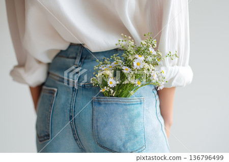 Bouquet of spring flowers tucked into jeans pocket on a casual young woman celebrating Mother's Day. Spring, freshness, romance and awakening concept 136796499