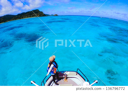 一位女子站在船頭，眺望著清澈碧綠的海水，遠方是熱帶風光。 136796772