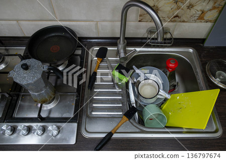 Cluttered kitchen sink with dirty dishes and sponges Cluttered kitchen sink with dirty dishes and sponges 136797674