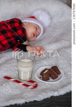 Sleeping toddler in santa hat with milk and cookies 136797680