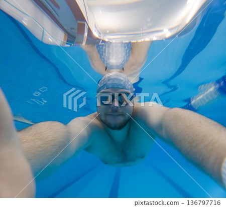 Underwater selfie of swimmer in blue pool with goggles Underwater selfie of swimmer in blue pool with goggles 136797716