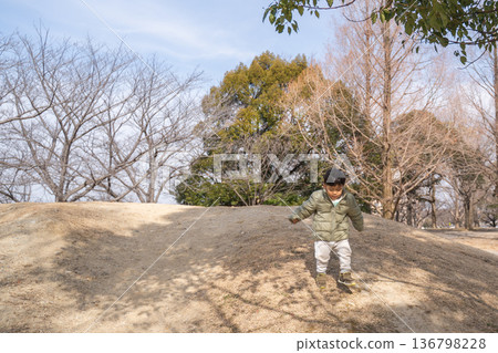 A child running down a dirt mountain in the park A child running down a dirt mountain in the park 136798228