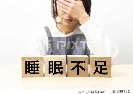 一位身穿圍裙的女子手持一塊寫著「睡眠不足」的牌子 136799958
