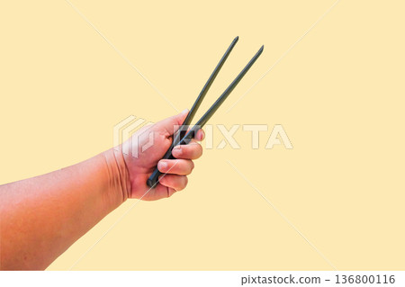 Black serving kitchen silicone tongs in hand with color background. Black serving kitchen silicone tongs in hand with color background. 136800116