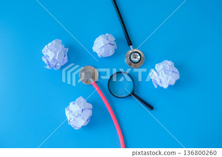 Stethoscope with crumpled sheet of paper and magnifying glass. Stethoscope with crumpled sheet of paper and magnifying glass. 136800260