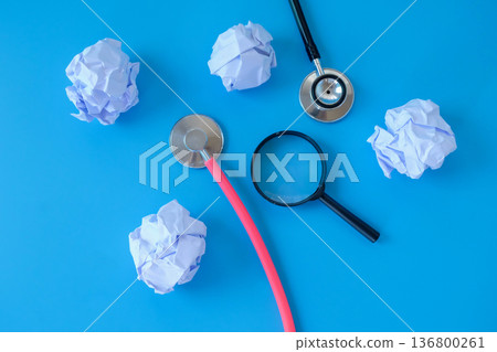 Stethoscope with crumpled sheet of paper and magnifying glass. Stethoscope with crumpled sheet of paper and magnifying glass. 136800261