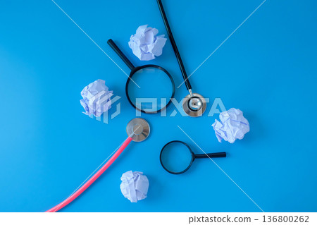 Stethoscope with crumpled sheet of paper and magnifying glass. Stethoscope with crumpled sheet of paper and magnifying glass. 136800262