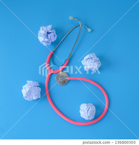 Stethoscope with crumpled sheet of paper on blue background. Stethoscope with crumpled sheet of paper on blue background. 136800303