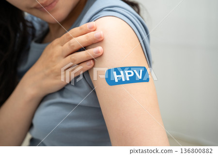 HPV, Human papillomavirus, Asian young woman receiving vaccine with blue bandage. HPV, Human papillomavirus, Asian young woman receiving vaccine with blue bandage. 136800882