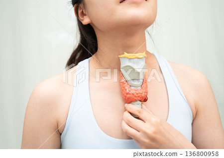 Hyperthyroidism, Overactive Thyroid, Thyroid Lymphoma, Asian woman with thyroid gland human anatomy model. Hyperthyroidism, Overactive Thyroid, Thyroid Lymphoma, Asian woman with thyroid gland human anatomy model. 136800958