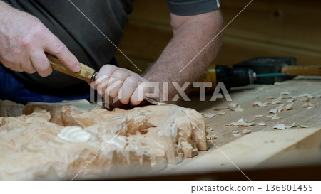 Artisan carves pattern, Master woodworker skillfully creates elegant motifs using precise tools, Seasoned craftsman delicately forms ornate decorative patterns in wood with steady strikes Artisan carves pattern, Master woodworker skillfully creates elegant motifs using precise tools, Seasoned craftsman delicately forms ornate decorative patterns in wood with steady strikes 136801455