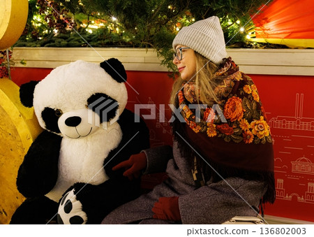 Creating joyful memories with a friendly panda plush during a winter evening in a festive setting 136802003