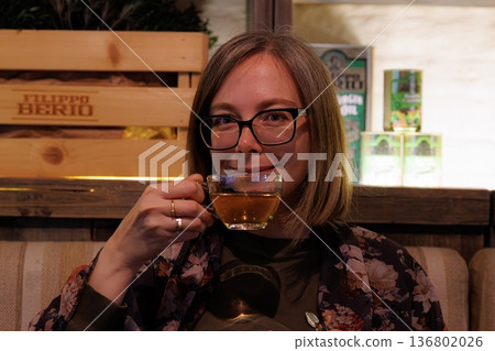 Enjoying a warm cup of herbal tea in a cozy cafe on a leisurely afternoon 136802026