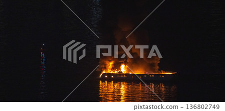 A motor yacht burns on dark water at night 136802749