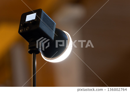 Close-up of a studio lamp spotlight emitting a warm LED glow on an adjustable stand Close-up of a studio lamp spotlight emitting a warm LED glow on an adjustable stand 136802764
