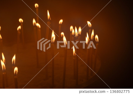 Prayer candles glow in the dark interior of an Orthodox church Prayer candles glow in the dark interior of an Orthodox church 136802775