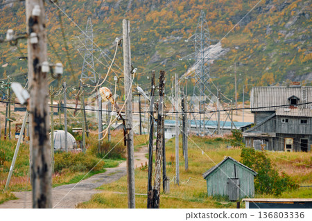 Weathered wooden houses in Teriberka at dusk, Russia, Kola Peninsula, evoke a bygone era, standing as silent witnesses to the passage of time. Teriberka's historical architecture concept 136803336