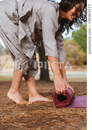 Woman Rolling Yoga Mat Outdoors in Preparation Woman Rolling Yoga Mat Outdoors in Preparation 136803517
