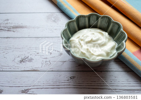 Natural fresh white greek yogurt in porcelain green plate on the wood table with napkin for healthy breakfast. Food concept. Natural fresh white greek yogurt in porcelain green plate on the wood table with napkin for healthy breakfast. Food concept. 136803581