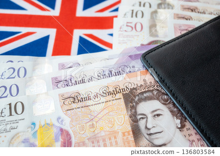 Black partmone with british pound money and flag. United Kindom bills in leather wallet for commerce concept. Black partmone with british pound money and flag. United Kindom bills in leather wallet for commerce concept. 136803584