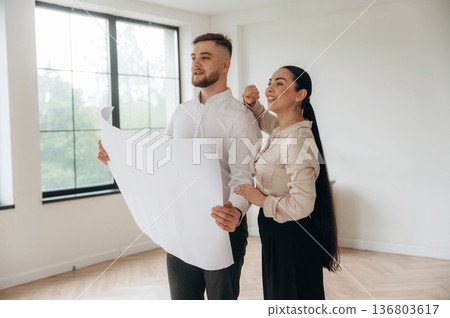 Big plan in hands. Man and woman are in the modern new room, conception of business Big plan in hands. Man and woman are in the modern new room, conception of business 136803617
