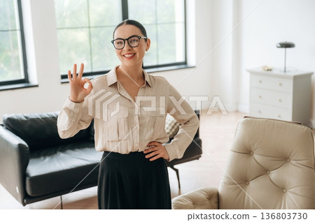 Okay hand sign. Woman in formal clothes is in the modern big room 136803730