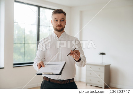 Pen in hand, sign the deal, buy new home. Real estate agent is in the new room Pen in hand, sign the deal, buy new home. Real estate agent is in the new room 136803747