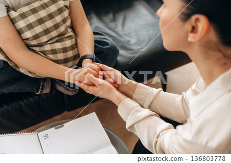 Support conception. Close up view of woman psychologist that is supporting young girl by holding her hands 136803778