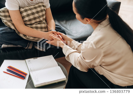 Support conception. Close up view of woman psychologist that is supporting young girl by holding her hands 136803779