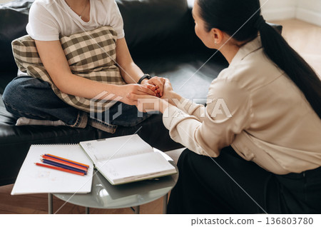 Support conception. Close up view of woman psychologist that is supporting young girl by holding her hands 136803780