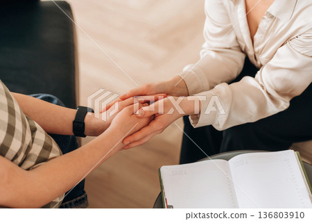 Close up view of woman psychologist that is supporting young girl by holding her hands 136803910