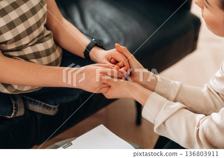 Support conception. Close up view of woman psychologist that is supporting young girl by holding her hands Support conception. Close up view of woman psychologist that is supporting young girl by holding her hands 136803911