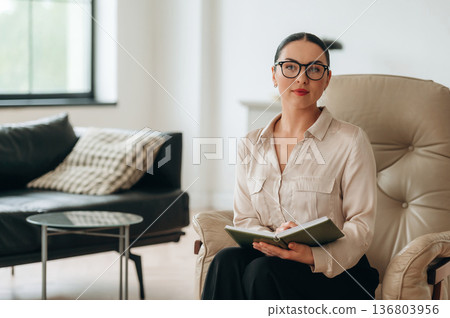 In glasses, front view. Woman in formal clothes is in the modern big room 136803956
