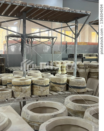 Clay molds and unfinished pottery are displayed in a bustling ceramics workshop where skilled artisans create beautiful pieces 136804094
