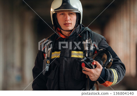 Firefighter in professional equipment is indoors in abandoned building 136804140