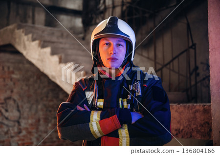 Looking forward, standing. Firefighter in professional equipment is indoors in abandoned building 136804166